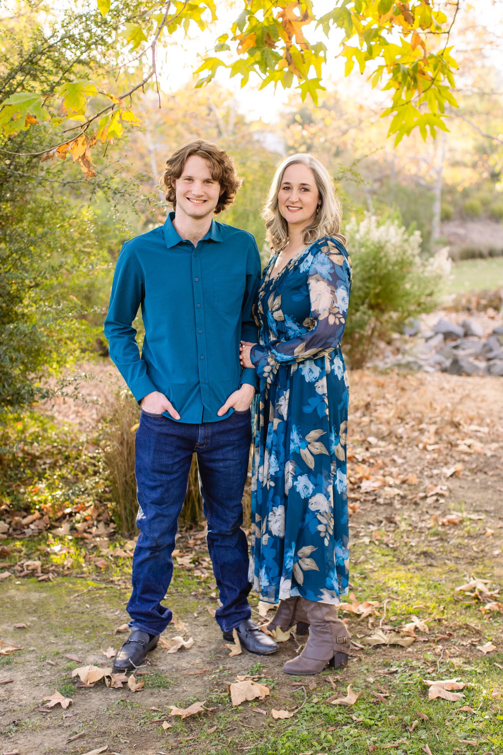 Jennifer and Jacob pose together with a backdrop of flowers, rocks, and trees on a sunny day.