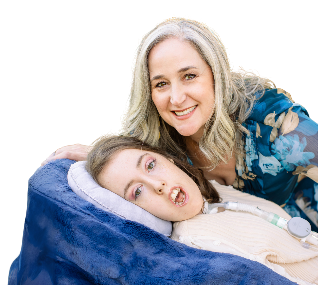 Jennifer and Kennedy swan pose together. Kennedy is laying down in her wheelchair, and Jennifer is standing over her smiling.