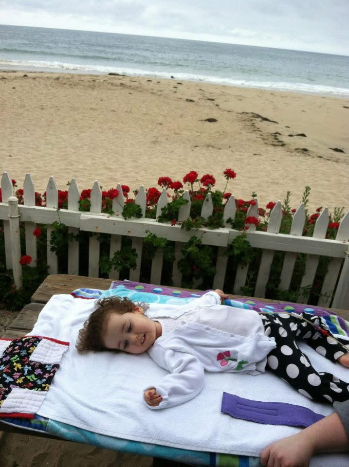 A young kennedy lays on a towel at the beach.