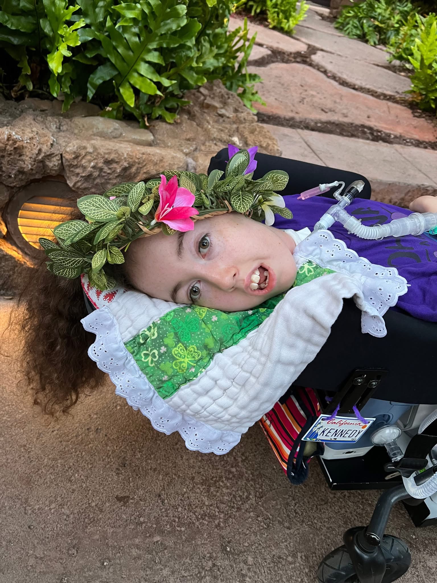 Kennedy in her wheelchair with leaves and a flower decorating her hair.