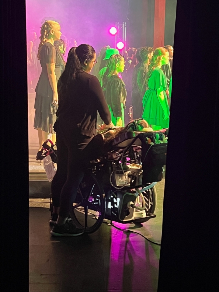 A view from backstage of Kennedy performing with her school's choir on stage.