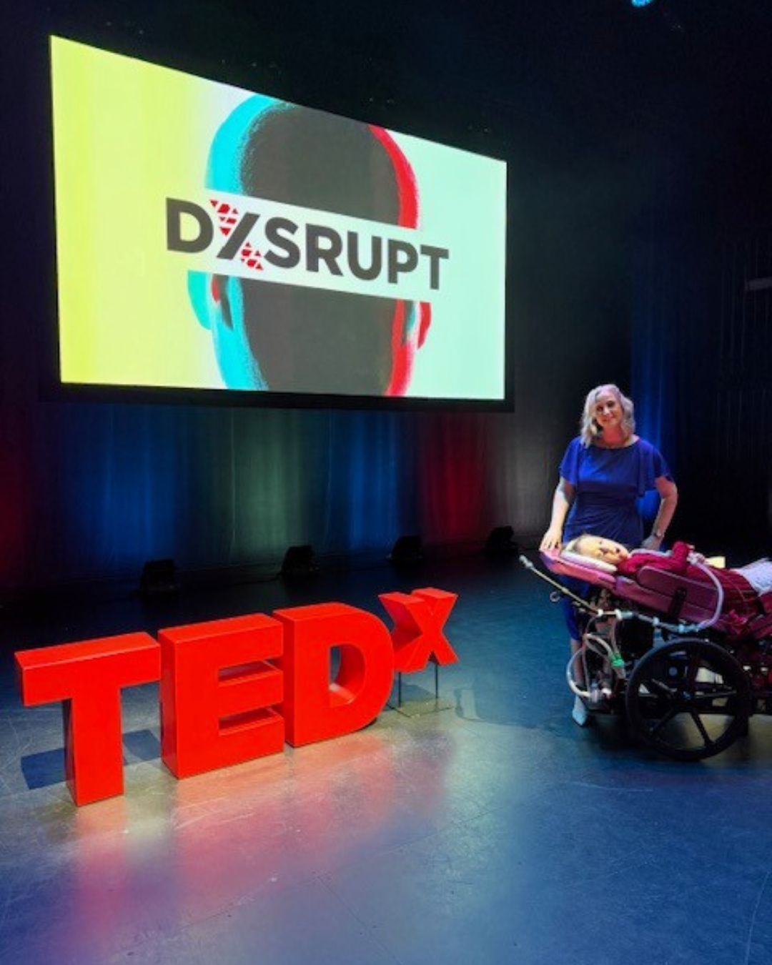Jennifer and Kennedy standing in front of TEDx Disrupt sign.