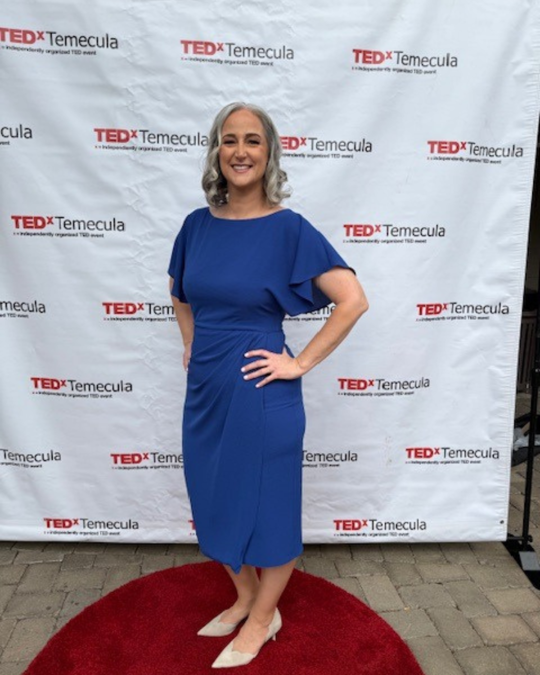 Jennifer posing in a blue dress at the TEDx conference.